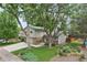 Landscaped front yard of gray home with brick accents and a long concrete driveway at 6514 Zinnia St, Arvada, CO 80004