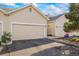 Attached garages of the townhome featuring asphalt driveways, a small garden, and siding at 212 Quari St, Aurora, CO 80011