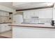 Bright kitchen featuring white cabinetry, white appliances and a breakfast bar with wood trim at 372 Vance St, Lakewood, CO 80226