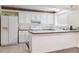 White kitchen features a breakfast bar, ample cabinet space, and modern appliances at 372 Vance St, Lakewood, CO 80226