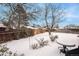 Snow-covered backyard with a patio table and shrubs at 13068 Dyanna Dr, Thornton, CO 80241