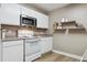 Bright kitchen with white cabinetry, stainless steel microwave, and modern floating shelves at 12914 Ironstone Way # 102, Parker, CO 80134