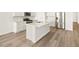 Modern kitchen with stainless appliances, island with sink, and hardwood flooring at 9099 Pitkin St, Commerce City, CO 80022