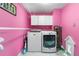 Bright pink laundry room featuring white washer and dryer, and convenient overhead cabinets at 7300 W Stetson Pl # 46, Littleton, CO 80123