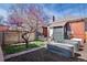 A backyard with two gardening troughs and an ornamental tree with light purple flowers, and a brick home at 328 S Lincoln St, Denver, CO 80209