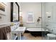 Bright bathroom with classic clawfoot tub, pedestal sink, and white tiled walls at 328 S Lincoln St, Denver, CO 80209