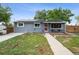 Charming exterior of home with solar panels, well-maintained lawn, sidewalk, and a red front door at 3930 S Hazel Ct, Englewood, CO 80110
