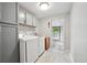 Bright laundry room with front-load washer and dryer, gray cabinets, and door to backyard at 3930 S Hazel Ct, Englewood, CO 80110