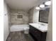 Updated bathroom featuring tiled walls and floors, a tub with shower, and a dark wood vanity at 5344 Wheeling St, Denver, CO 80239