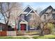 Charming two-story home with a red door, picket fence and blossoming tree in the front yard at 3142 W 26Th Ave, Denver, CO 80211
