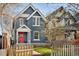 Charming two-story home with a red door, blossoming tree and a quaint picket fence at 3142 W 26Th Ave, Denver, CO 80211