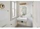 Elegant powder room with a pedestal sink, gold-toned fixtures, and modern wall mirror at 3142 W 26Th Ave, Denver, CO 80211