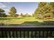 Relaxing back yard view of golf course through wood railing with trees in distance at 5845 W Mansfield Ave # 259, Denver, CO 80235