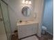 Bright bathroom features a glass shower stall and a vanity with a round mirror at 5845 W Mansfield Ave # 259, Denver, CO 80235