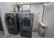 A modern laundry room showcasing gray front load washer and dryer with overhead shelving and cleaning accessories at 5845 W Mansfield Ave # 259, Denver, CO 80235