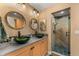 Bathroom featuring dual sinks, circular mirrors, granite countertop, mosaic tile accents and a glass shower at 32094 Christopher Ln, Conifer, CO 80433