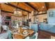 Open concept dining room with wood ceiling beams, stone fireplace, and views to kitchen at 32094 Christopher Ln, Conifer, CO 80433