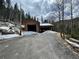 Two-car garage with wooden siding and green doors, accessible by a sloping driveway at 32094 Christopher Ln, Conifer, CO 80433