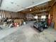 Bright garage interior featuring exposed wooden beams, work area, and an ATV parked inside at 32094 Christopher Ln, Conifer, CO 80433