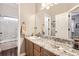 Well-lit bathroom with granite countertops, wooden cabinets, and tub with white tile surround at 16650 Shadow Wood Ct, Hudson, CO 80642