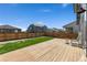 Spacious backyard with a wooden deck, well-maintained lawn, and privacy fence at 6150 Sugarloaf St, Brighton, CO 80601