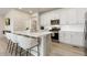 Bright kitchen featuring white cabinetry, stainless steel appliances, island seating, and modern fixtures at 6150 Sugarloaf St, Brighton, CO 80601