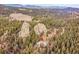 Majestic aerial view of the mountain home surrounded by trees and rock outcroppings, and distant mountain range views at 24354 Eagle Cliff Trl, Conifer, CO 80433