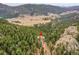 Stunning aerial view of a secluded home nestled in the mountains among tall pine trees and unique rock outcroppings at 24354 Eagle Cliff Trl, Conifer, CO 80433