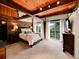 Bedroom with wood beams, large windows with mountain views, and sliding glass door to balcony at 24354 Eagle Cliff Trl, Conifer, CO 80433