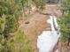 Aerial view of vacant horse pen, partially snow-covered, and surrounded by a wooden fence and mature pine trees at 24354 Eagle Cliff Trl, Conifer, CO 80433