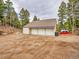 A three-car garage or outbuilding on the property offers ample storage and parking surrounded by mature trees at 24354 Eagle Cliff Trl, Conifer, CO 80433