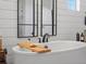 Close up view of a soaking tub with wood caddy in a modern farmhouse style bathroom at 1291 Fountain Ln, Erie, CO 80516