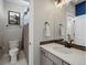 This well-lit bathroom includes a sink with dark hardware, a toilet, and a shower with a patterned curtain at 1291 Fountain Ln, Erie, CO 80516