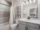 Bathroom featuring shower-tub combo with gray tiling, white vanity, mirror, and artwork at 1291 Fountain Ln, Erie, CO 80516