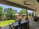 Inviting covered patio features stone flooring, ceiling fan, stylish dining set and outdoor lounge for elegant entertaining at 1291 Fountain Ln, Erie, CO 80516