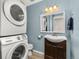 Cozy laundry room featuring stacked washer and dryer adjacent to charming half-bathroom with updated vanity at 9886 Appletree Pl, Thornton, CO 80260