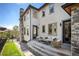 Comfortable outdoor patio seating area with view of a lush green lawn and stone accents on the home at 2136 S Juniper St, Lakewood, CO 80228