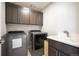 Well-lit laundry room with modern washer, dryer, utility sink and dark cabinetry for ample storage at 2136 S Juniper St, Lakewood, CO 80228