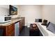 Finished basement wet bar with modern cabinets, stone countertops, and TV at 9170 Fox Fire Dr, Highlands Ranch, CO 80129