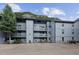 Three-story condominium with grey wood, balconies, gravel parking, and view of mountains in the background at 1901 Clear Creek Dr # F104, Georgetown, CO 80444