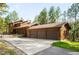 Three-car garage with a house featuring wood siding and a concrete driveway at 612 Nob Hill Trl, Franktown, CO 80116