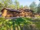 View of the back of a wooden house surrounded by lush greenery and mature trees at 612 Nob Hill Trl, Franktown, CO 80116