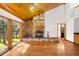 Open living room featuring a stone fireplace, wood ceilings, and scenic backyard views at 612 Nob Hill Trl, Franktown, CO 80116