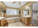 Bright bathroom featuring double sinks, large soaking tub, tiled floors, and neutral wall color at 7862 Stonedale Dr, Castle Pines, CO 80108