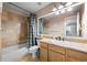 Well-lit bathroom featuring tiled shower and tub, a large mirror, and light wood cabinets at 7862 Stonedale Dr, Castle Pines, CO 80108