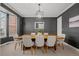 Elegant dining room with a large wooden table, stylish chairs, modern chandelier, dark gray accent wall and refined decor at 7862 Stonedale Dr, Castle Pines, CO 80108
