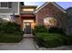 Inviting home entrance showcasing decorative bushes, brick accents, exterior lighting and a well-lit front door at 7862 Stonedale Dr, Castle Pines, CO 80108