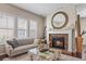 Cozy living room featuring a beautiful stone fireplace, large windows, and a comfortable couch at 7790 S Queensburg Way, Aurora, CO 80016