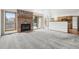 Open living room features brick fireplace, neutral carpet, and sliding glass door to the deck at 11285 Ranch Pl, Denver, CO 80234