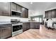 Well-equipped kitchen with stainless steel appliances, granite countertops, dark cabinets, and hardwood floors throughout at 56375 E 22Nd Pl, Strasburg, CO 80136